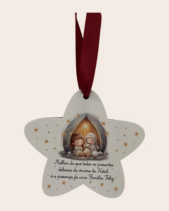 Enfeite em forma de estrela, branco, com o presépio ilustrado e a frase «Melhor do que todos os presentes debaixo da árvore de Natal é a presença de uma Família Feliz», pendurado por fita vermelha.